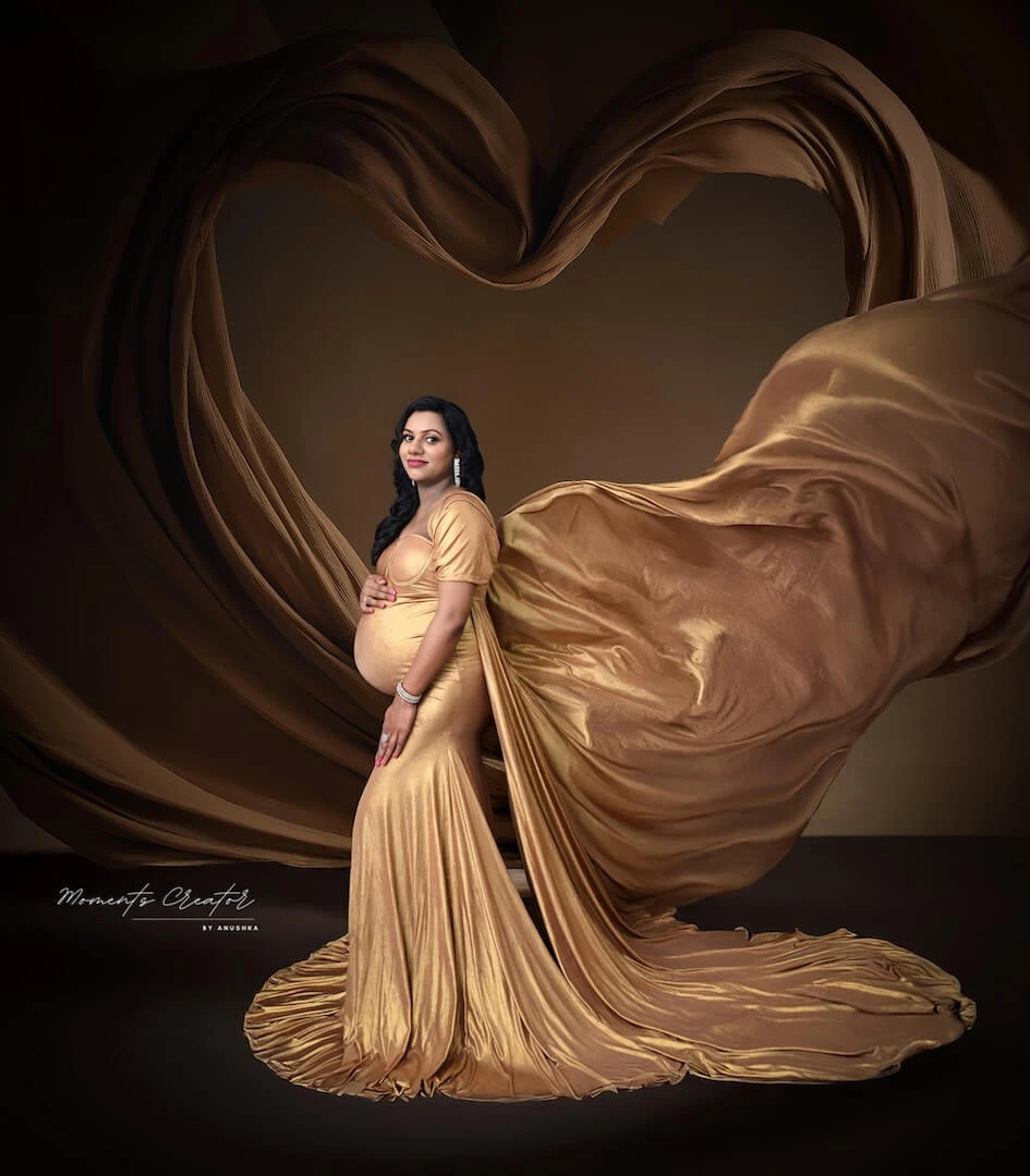 Expecting mother in a gold drape during a maternity photoshoot at the Moments Creator studio in Dwarka, Delhi