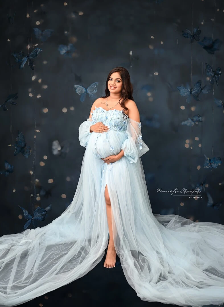 Sky blue gown maternity photoshoot with a butterfly backdrop at a Delhi NCR maternity studio